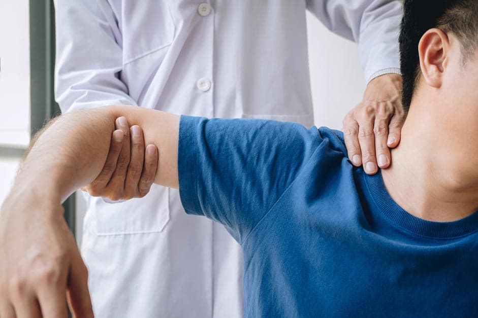 Arzt prüft Schulter von Patienten