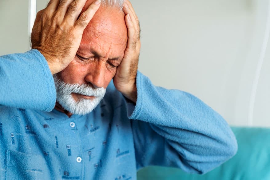 Senior hält mit seinen Händen sein Kopf fest