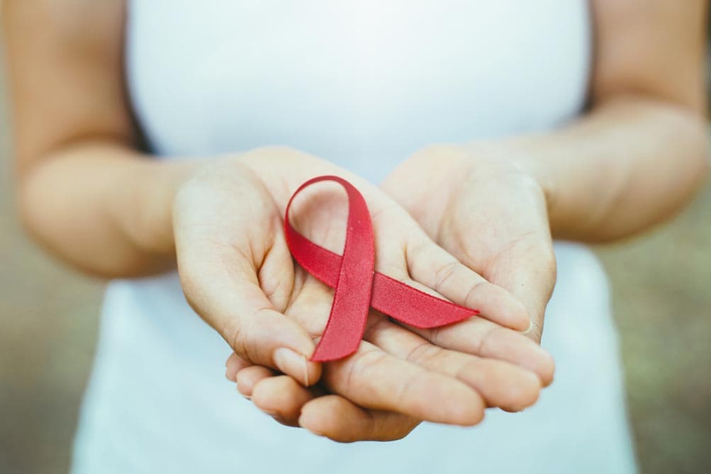 FRau hält rote Aids Schlaufe in den Händen
