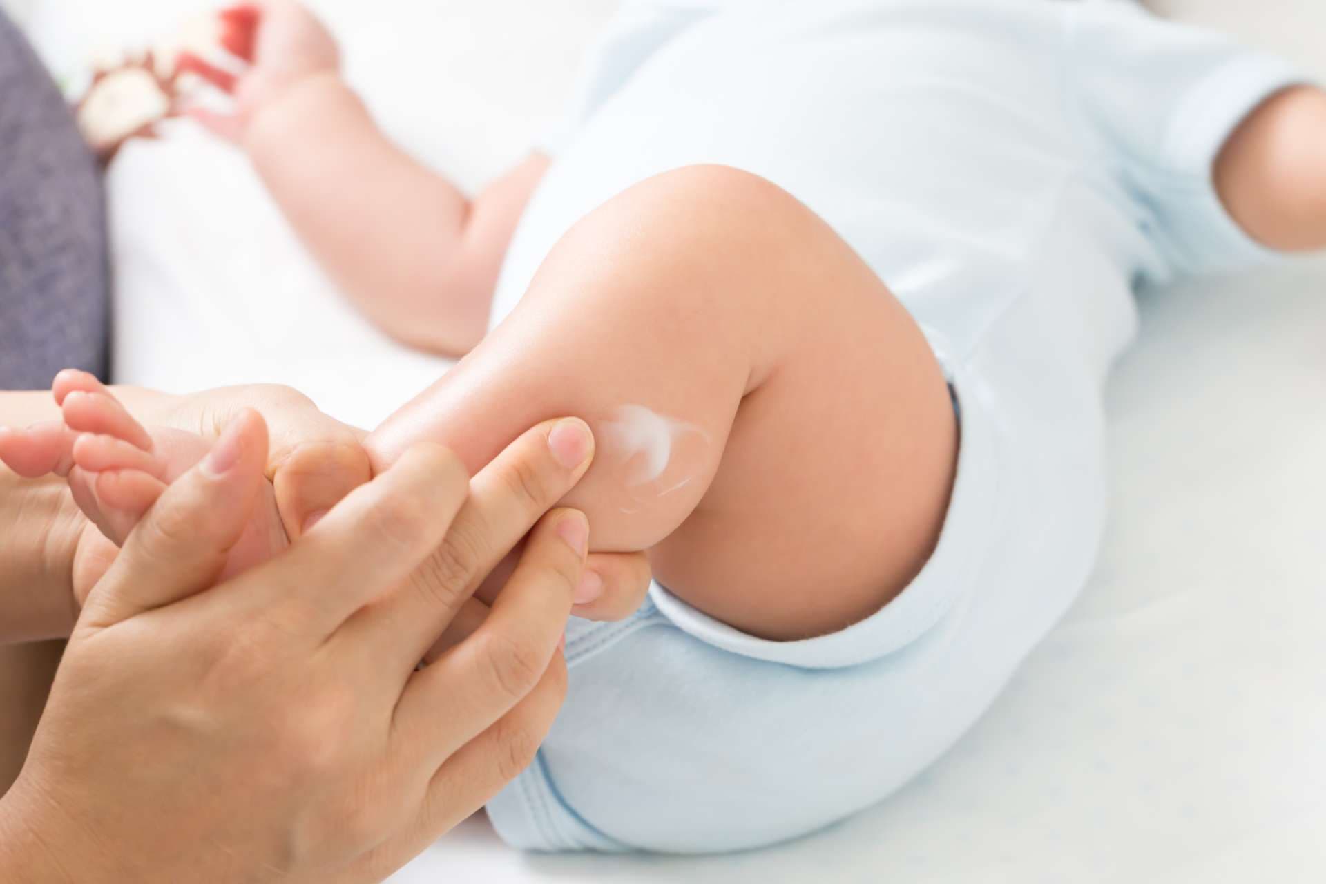 Mutter trägt Creme auf den Jungen auf, die hilft, die Hautbefeuchtung, die Hautpflege und das Feuchtigkeitscremekonzept aufrechtzuerhalten