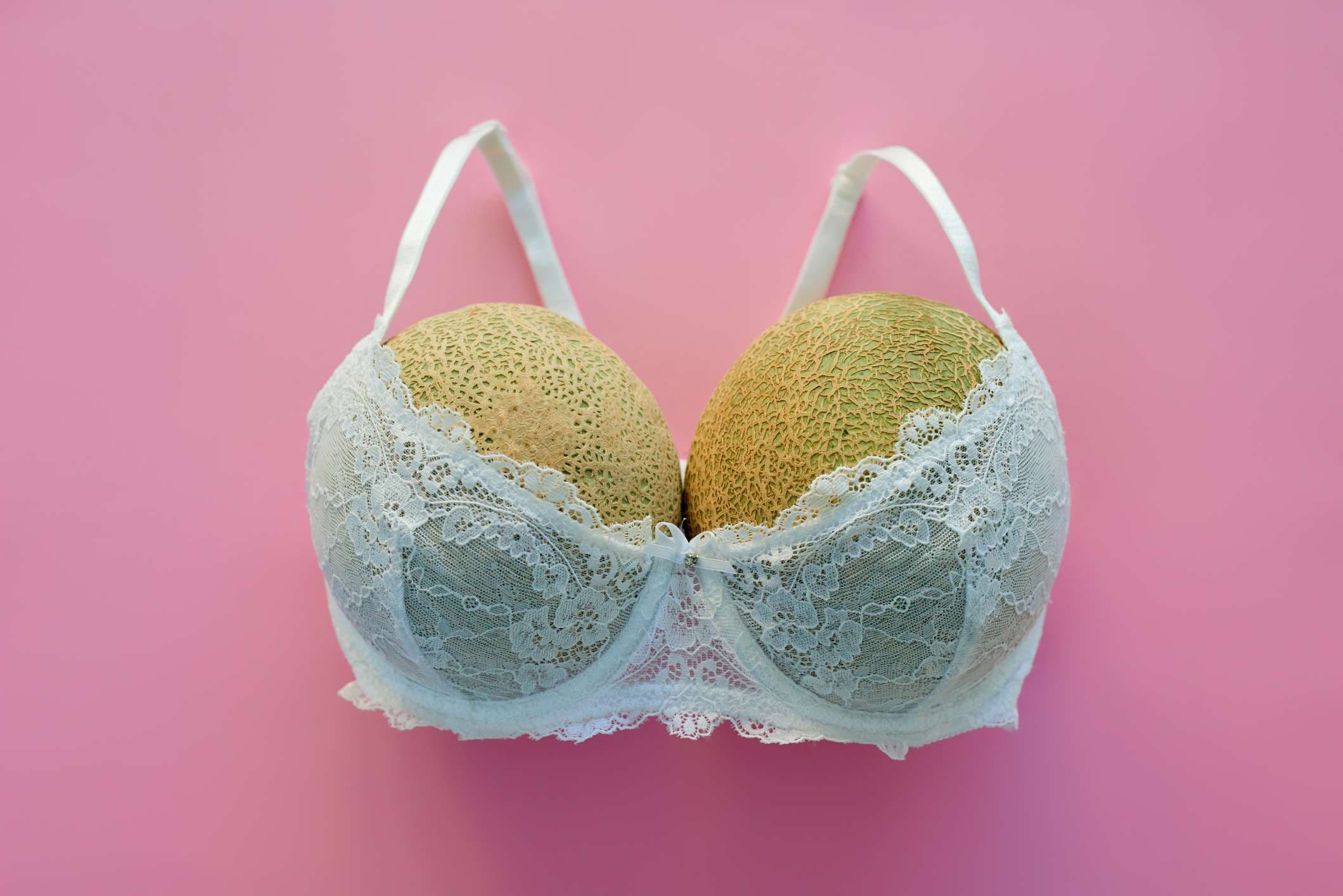 Studioaufnahme von Melonen in einem BH gegen einen rosa Hintergrund