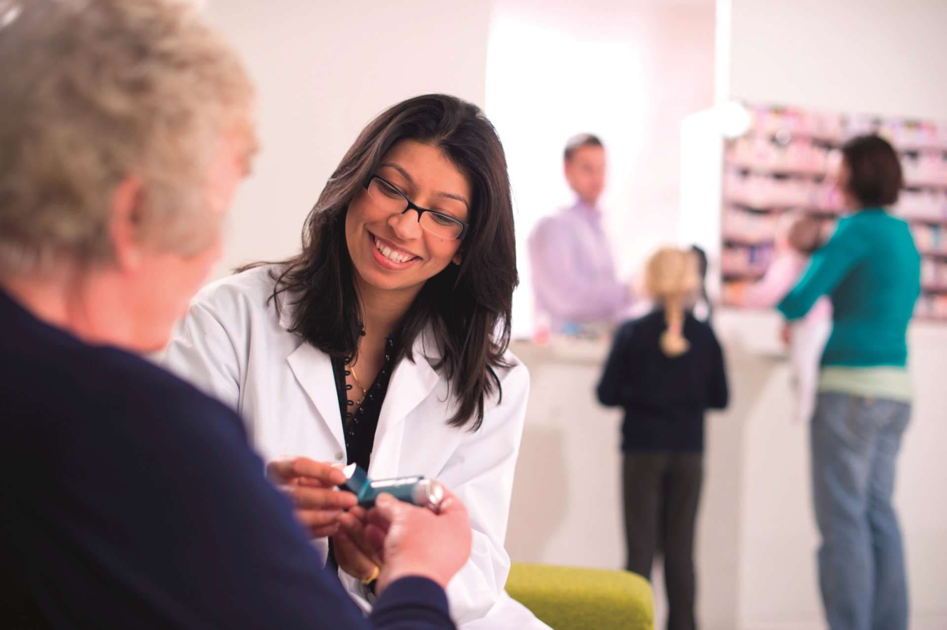 pharmacist demonstrates an inhaler to senior