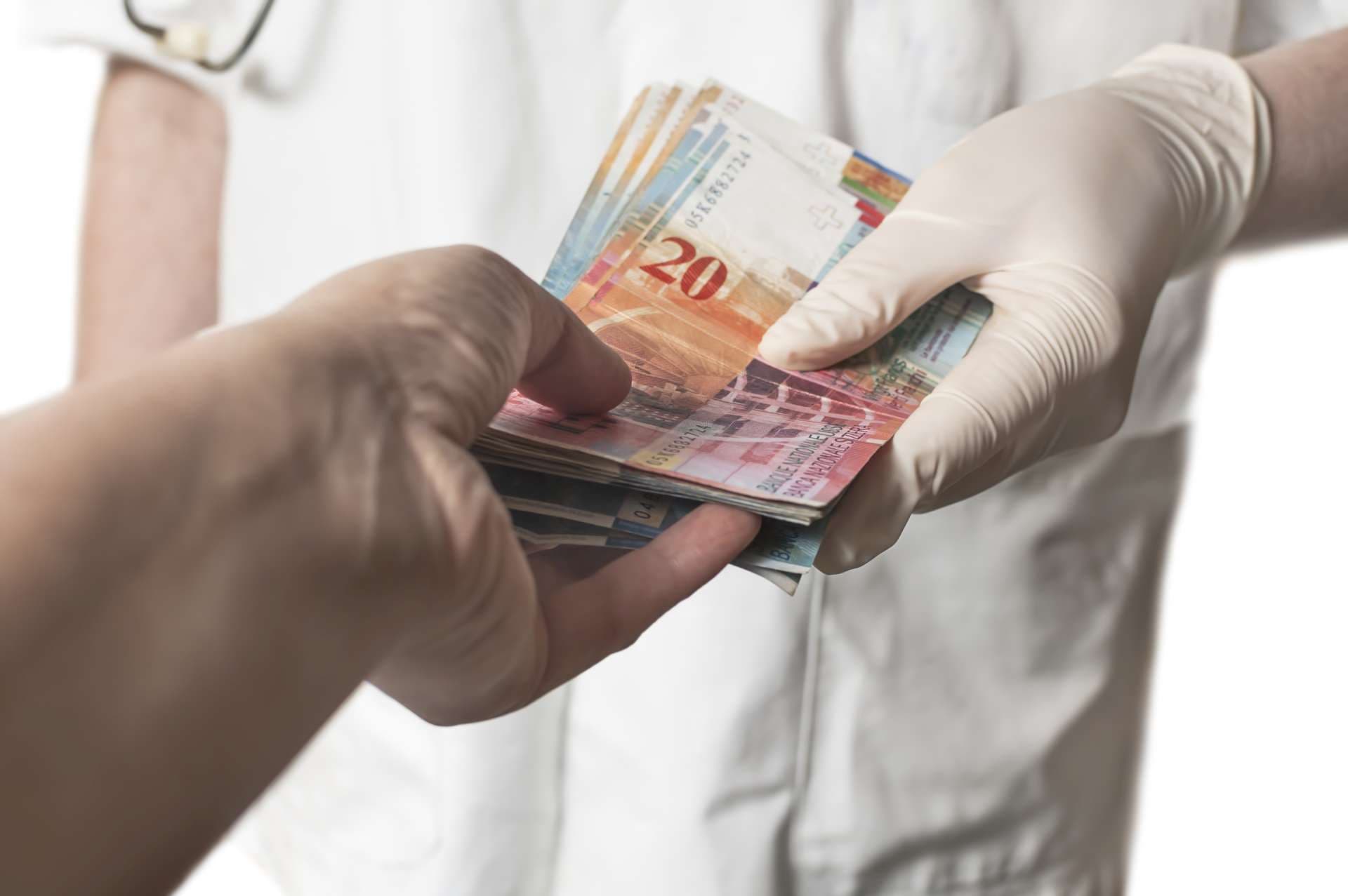 Arzt erhält eine große Menge Schweizer Banknoten als Bestechung. Korruption im Gesundheitswesen.