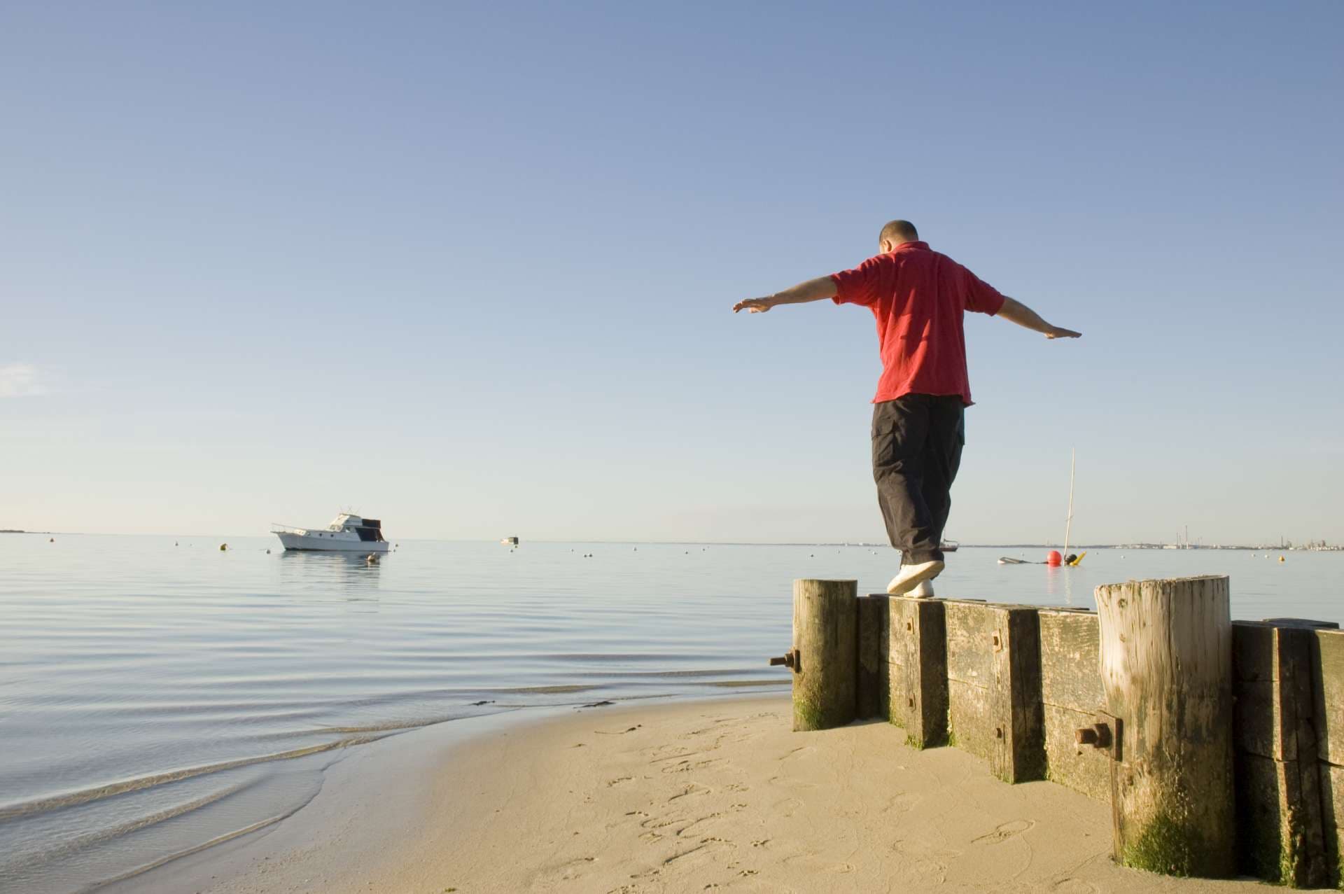 Mann, der einen Spaziergang auf dem Strand an einem Sommerabend nimmt.