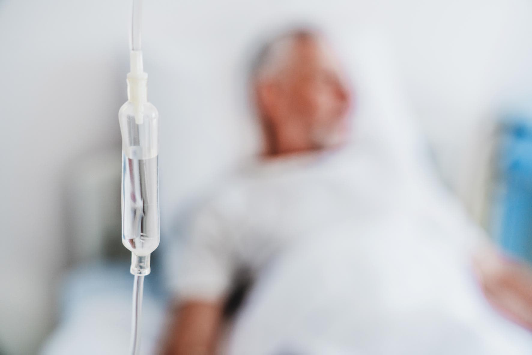 Nahaufnahme von iv Tropfer und Patient im Hintergrund