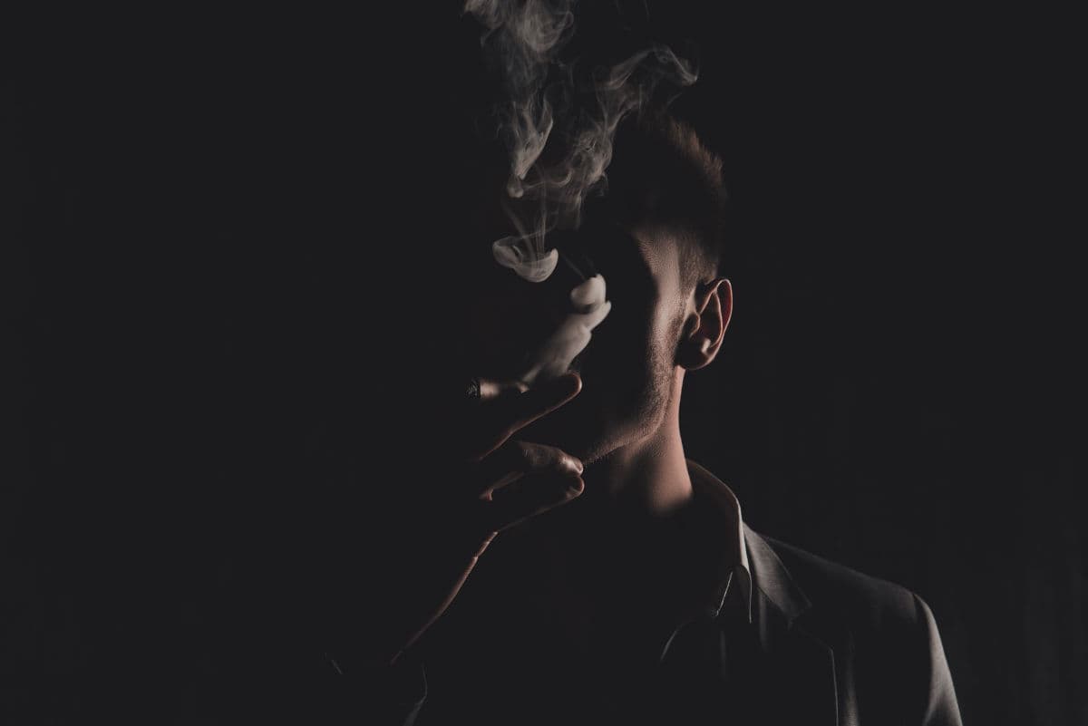 Mystery man with cigar and smoke isolated on black background