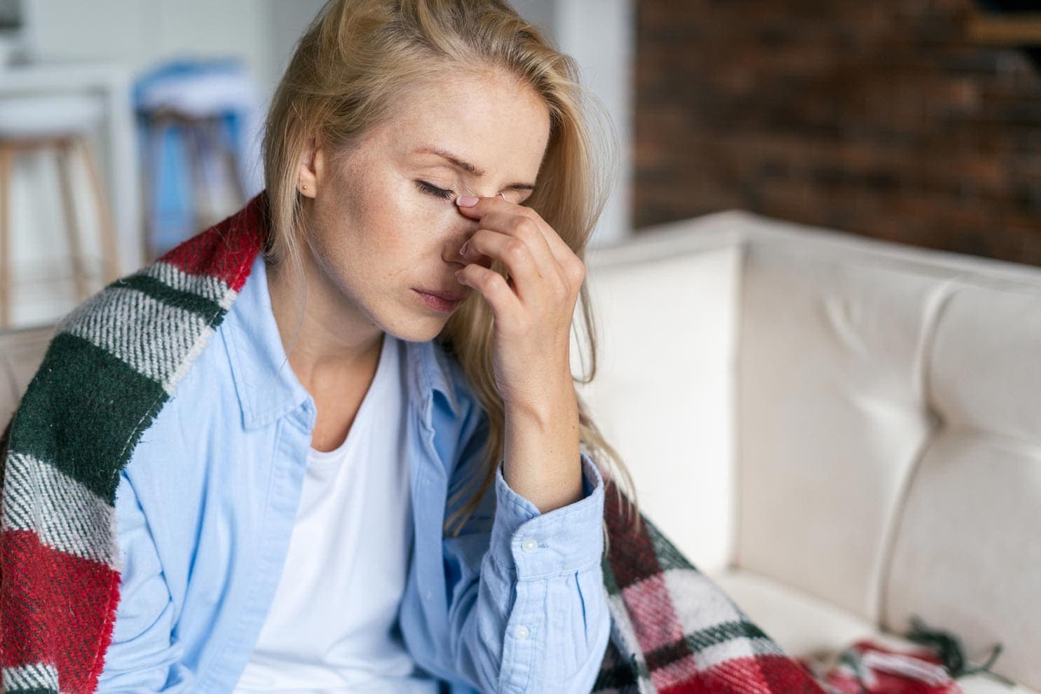 Frau hält sich ihre schmerzende Nase fest