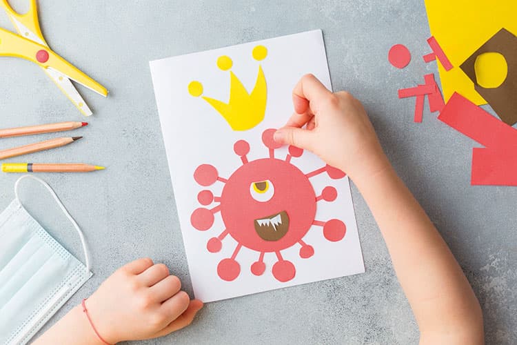 Blatt von oben auf einem Tisch mit Kinderhänden, die eine Viruszelle zeichnen