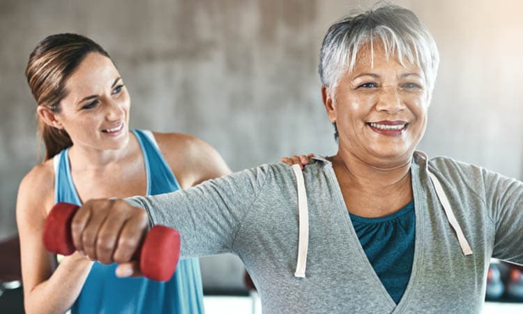 Shot of a senior woman using weights with the help of a physical therapist