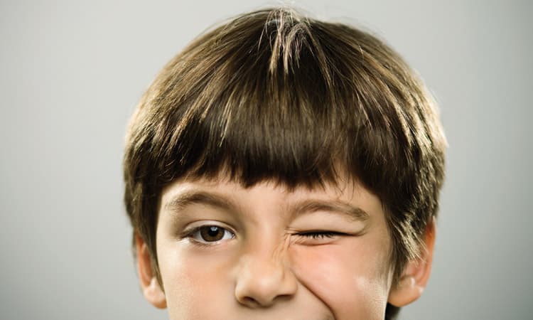 Kopf eines kleinen Jungens, der mit dem Auge zwinkert