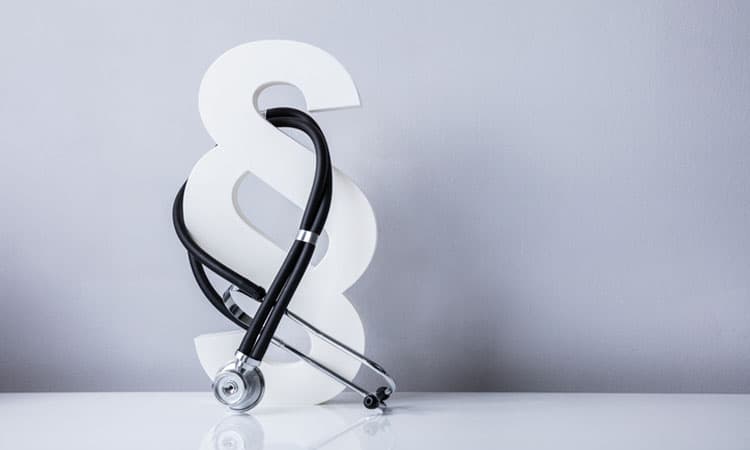 Close-up Of Stethoscope And Paragraph Symbol On Grey Background