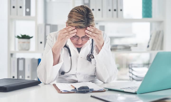 Cropped shot of an attractive young female doctor suffering with a headache while working in her office
