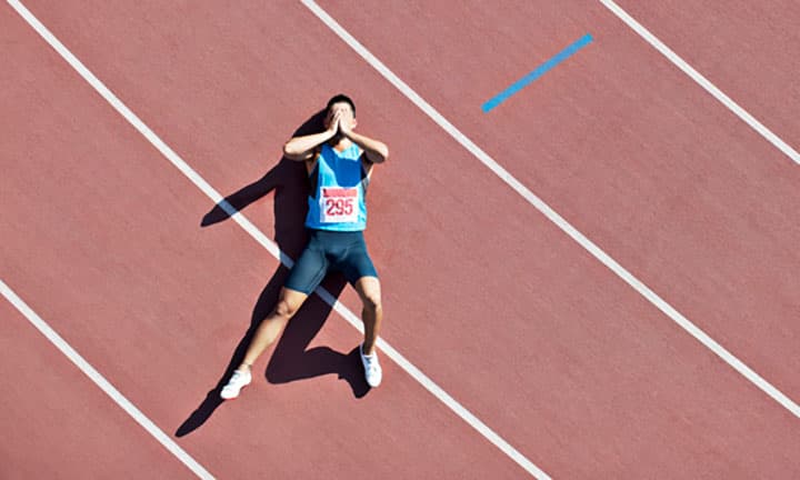 Sprint-Athlet liegt erschöpft auf der Sprintbahn
