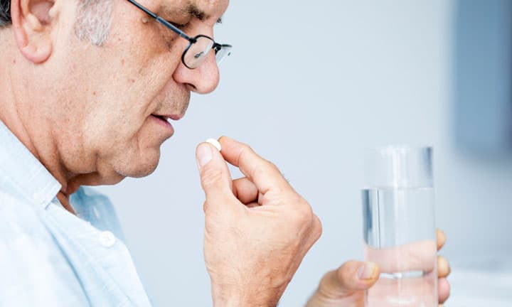 Old man taking a pill