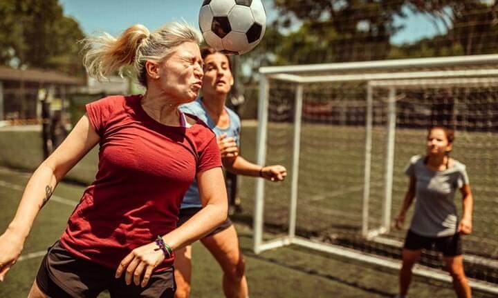 Female athlete scoring a soccer goal by heading the ball