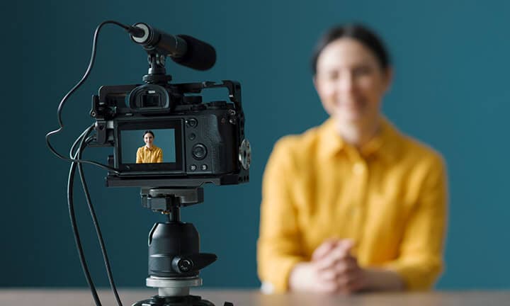 Smiling woman sitting in front of a camera and making a video blog
