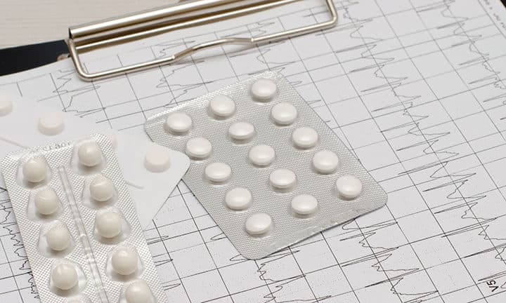 Medikamente auf Klemmbrett mit EKG-Auszügen