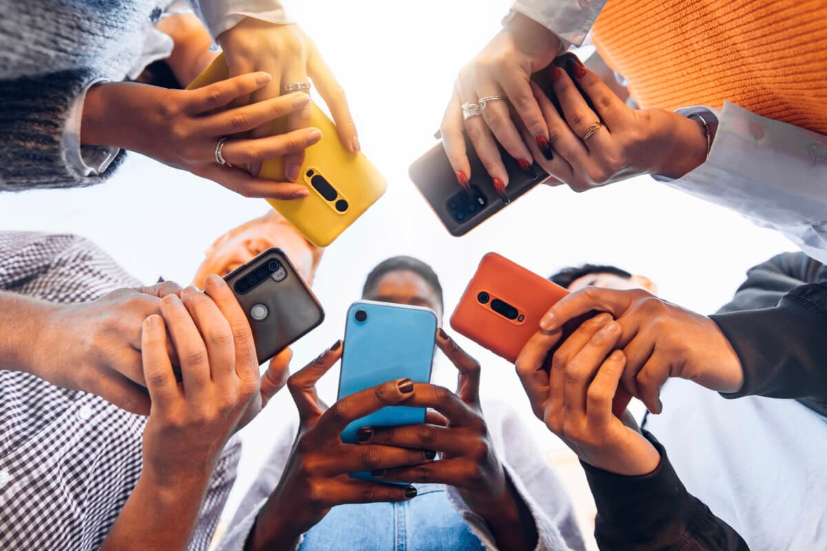 Teens in circle holding smart mobile phones – Multicultural young people using cellphones outside – Teenagers