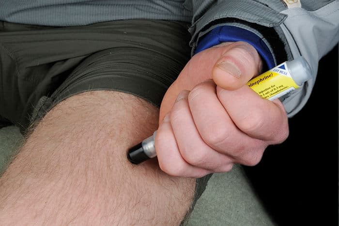 Mann spritzt sich Adrenalin mit einem Autoinjektor ins Bein
