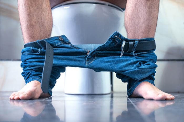Der Mann sitzt mit heruntergelassenen Hosen auf der Toilette. Durchfall.