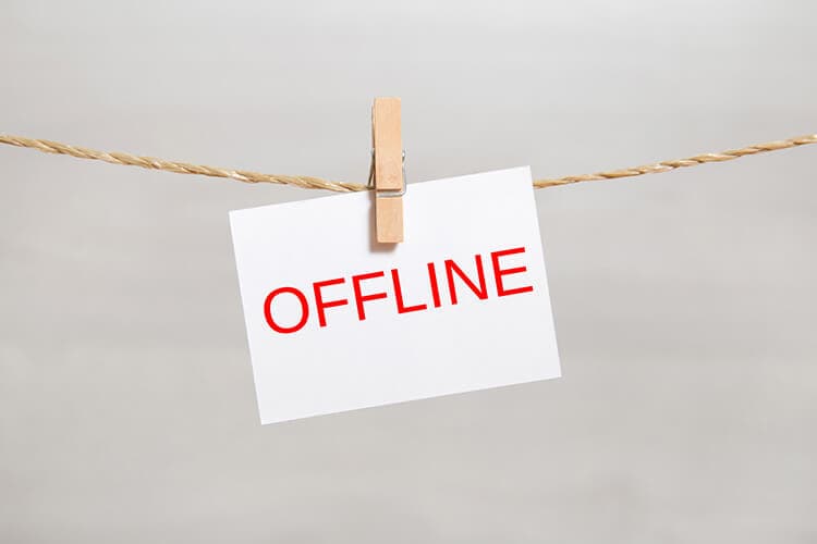 Ein Zettel mit der Schrift Offline hängt mit einer Wäscheklammer befestigt an einer Schnur.