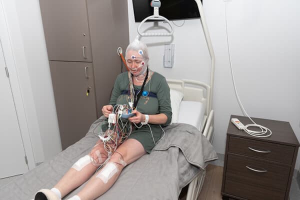 Une femme d'âge moyen mesure les ondes cérébrales et examine la polysomnographie dans un laboratoire du sommeil