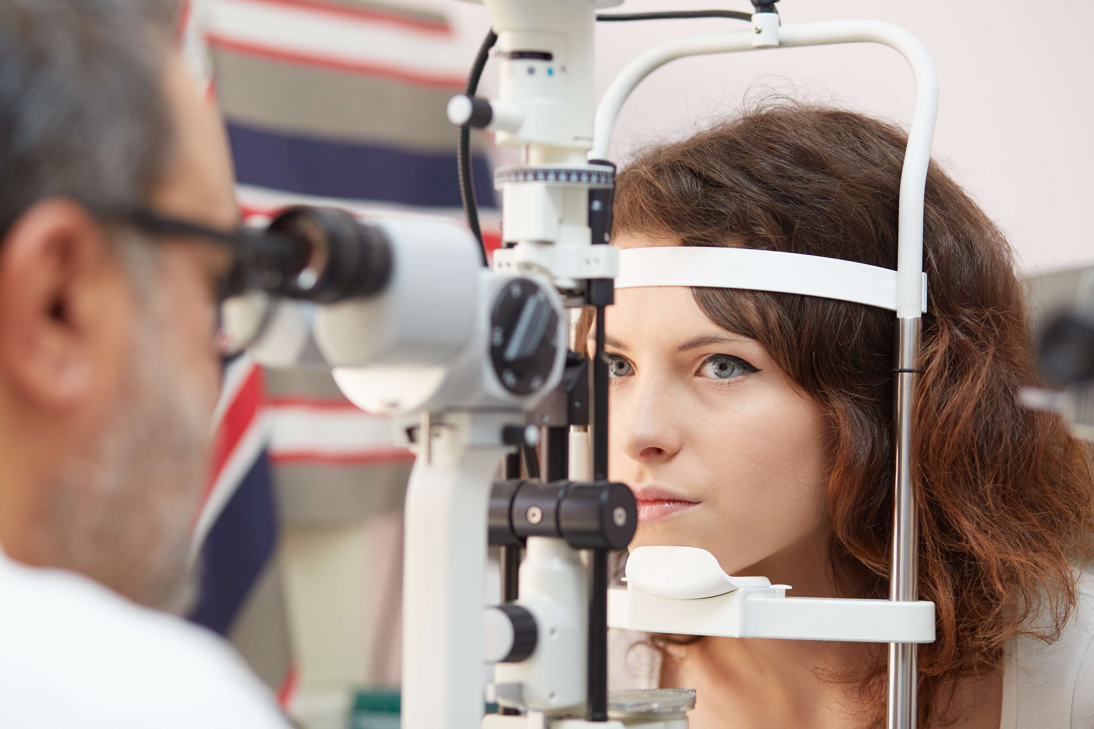 pretty young woman having her eyes examined by an eye doctor