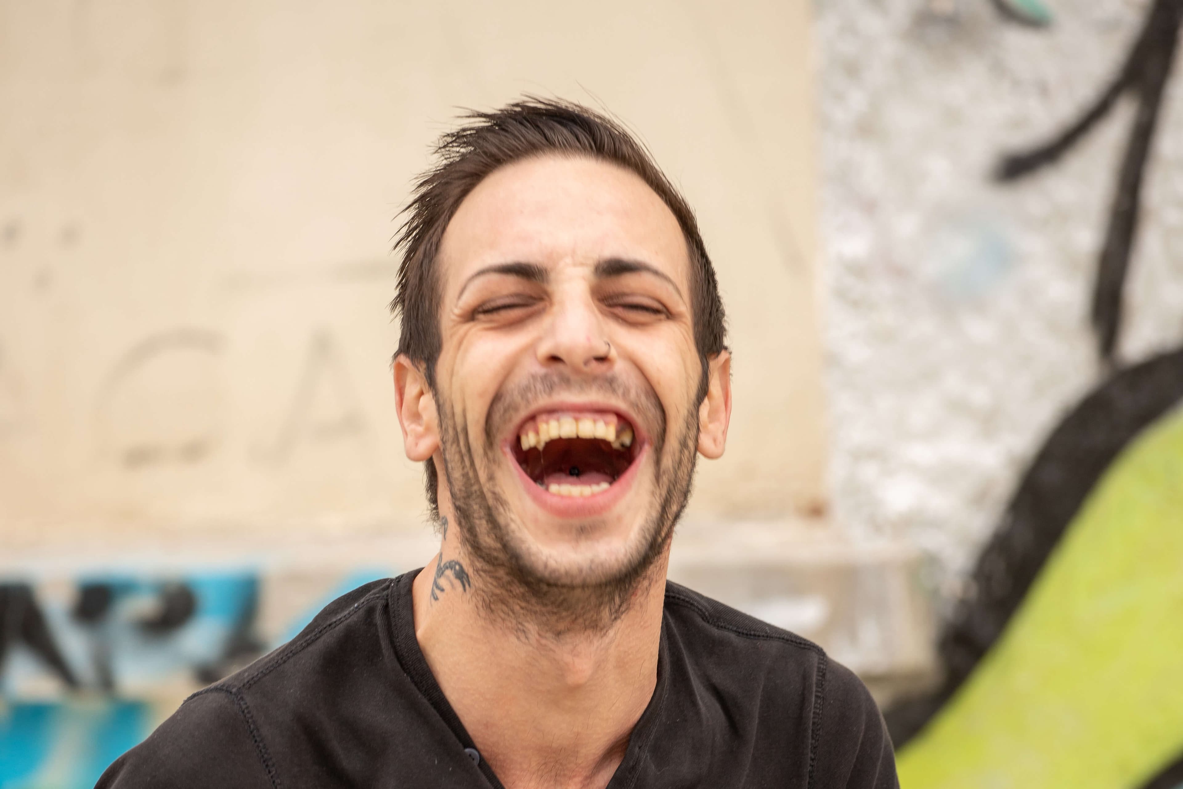Man in black t-shirt laughing out loud for the photo