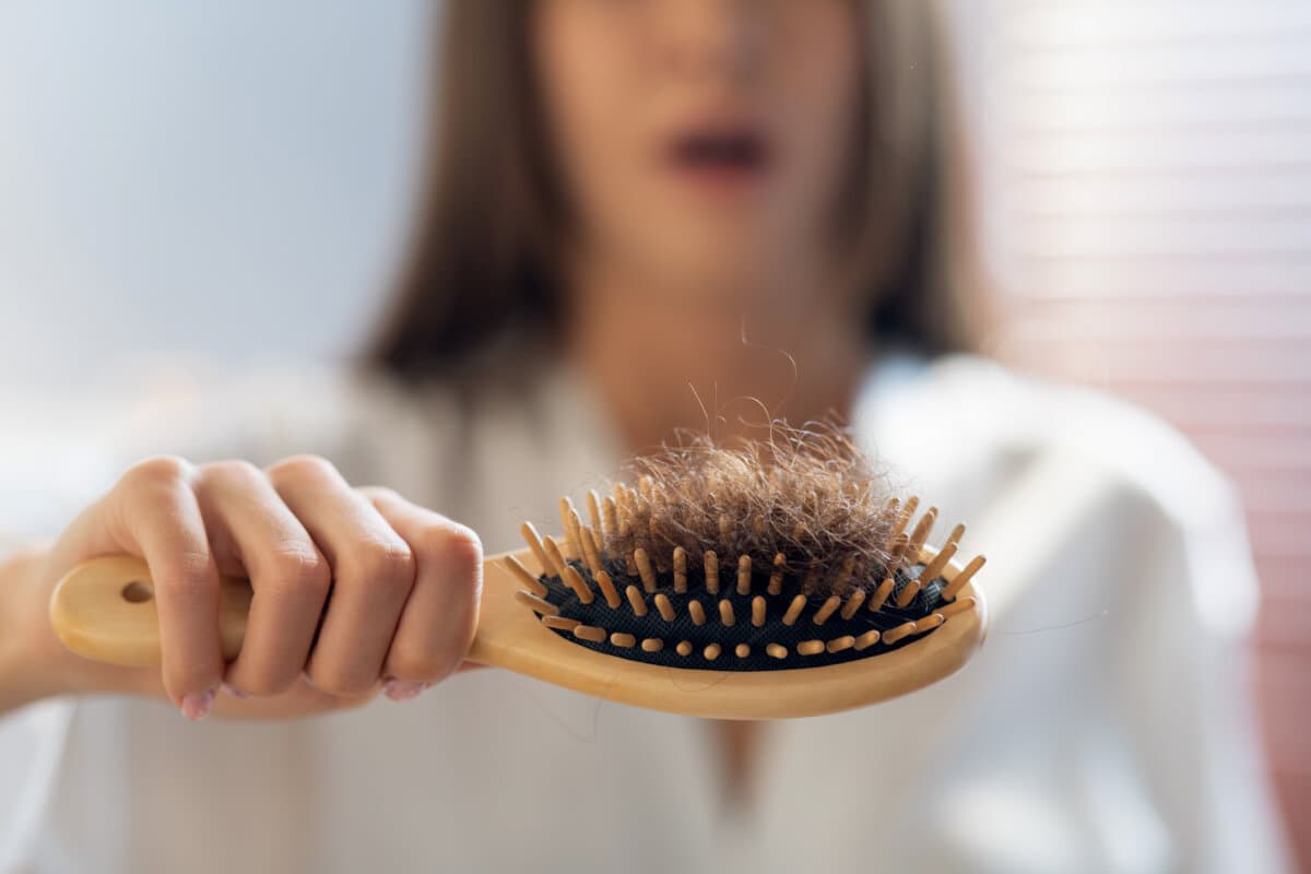 Haarausfall-Konzept. Besorgte Frau mit Kamm voller gefallener Haare nach dem Bürsten
