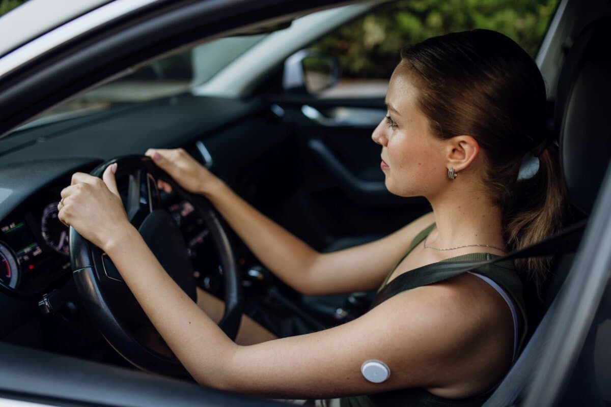 Frau mit Diabetes überwacht ihren Blutzucker während der Autofahrt.