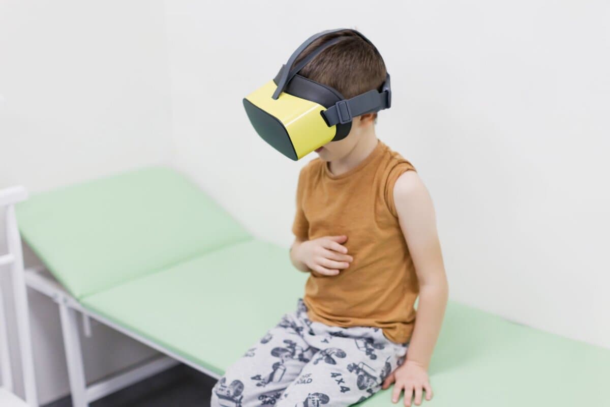 Ablenkung vor der Diagnostik: Ein Junge mit VR-Brille sitzt in der Klinik auf dem Sofa – moderner Einsatz von virtueller
