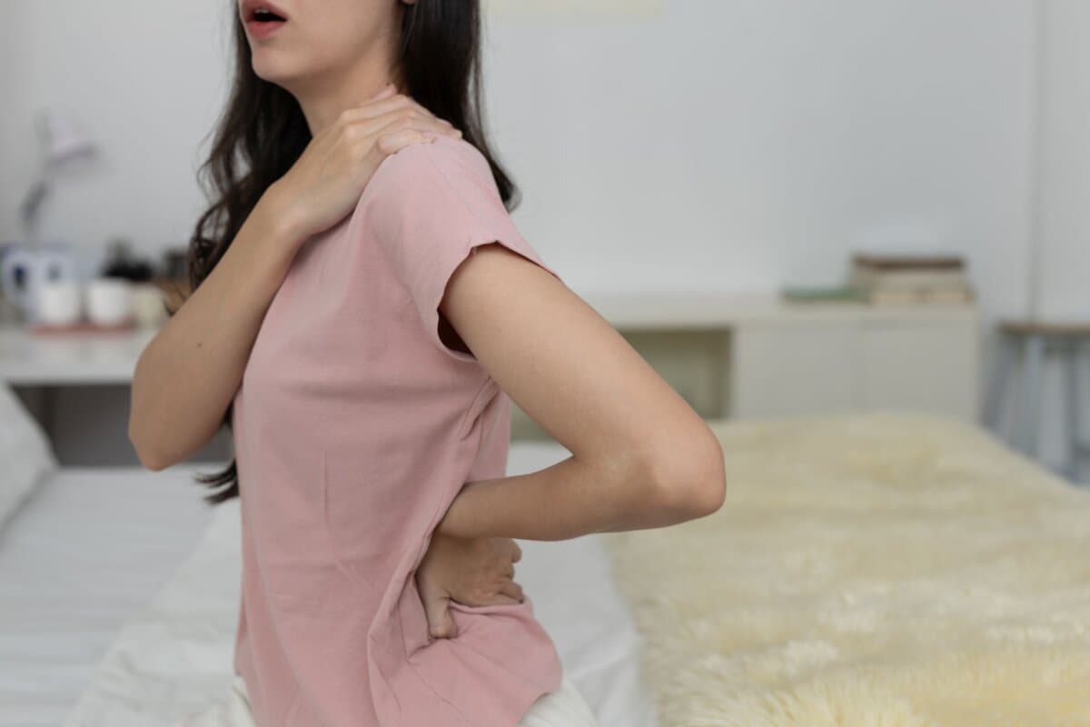 Junge Frau massiert ihren Nacken zur Linderung von Schmerzen und Muskelverspannungen.