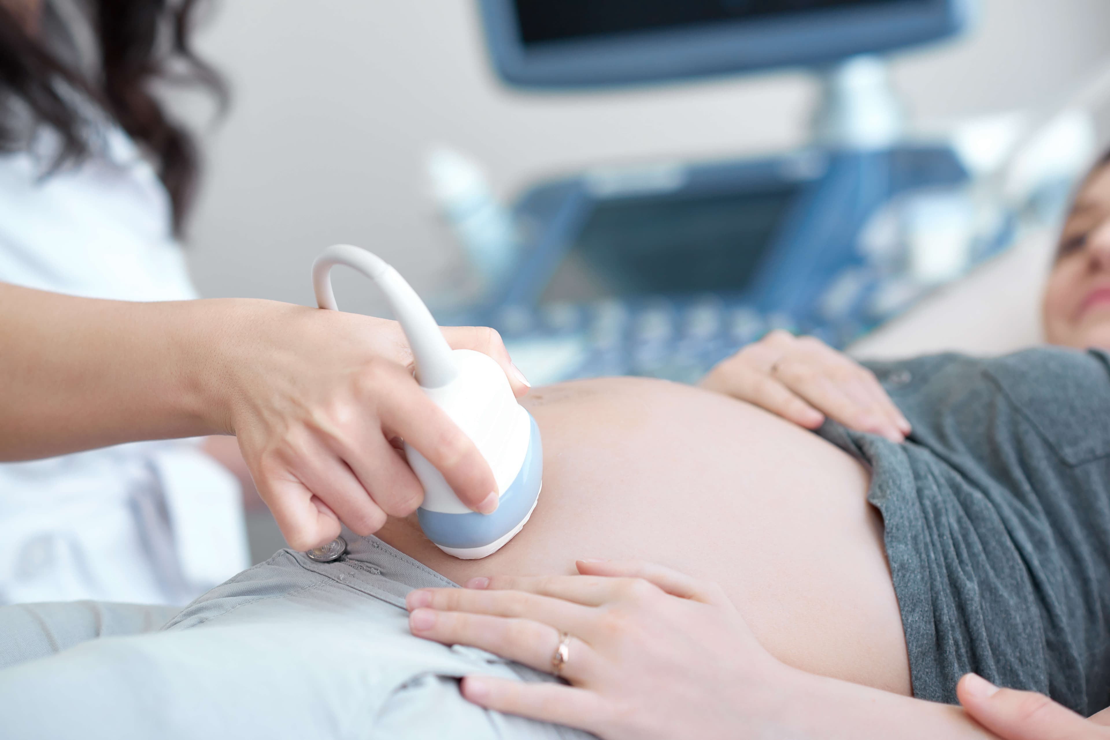Doctor using ultrasound equipment screening of pregnant woman.