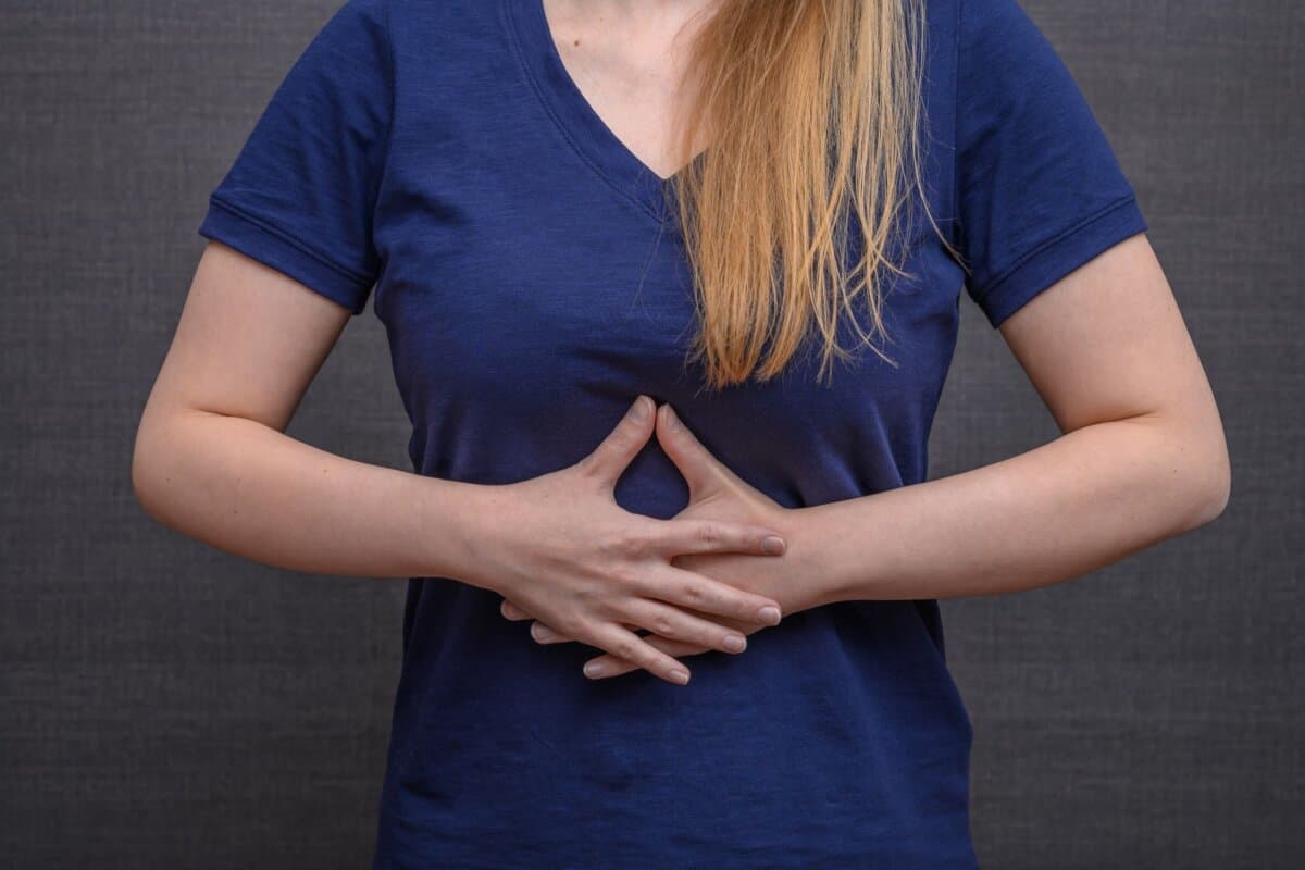 Junge Frau hält sich wegen Bauchschmerzen und Übelkeit den Unterbauch.