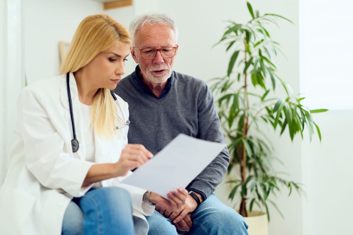 Ärztin bespricht mit einem älteren Patienten Untersuchungsergebnisse in der Sprechstunde.