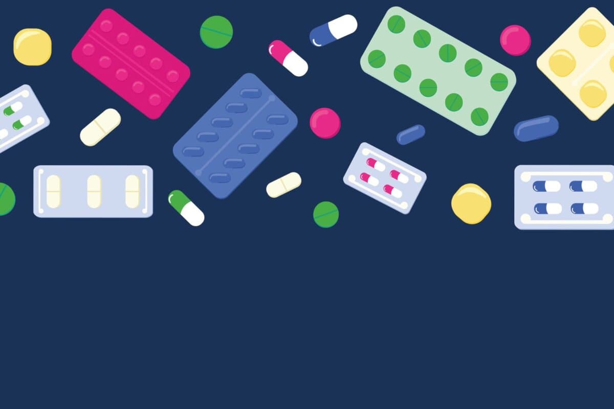 Bunte Tabletten, Kapseln und Blisterpackungen auf dunkelblauem Hintergrund – illustrative Darstellung pharmazeutischer