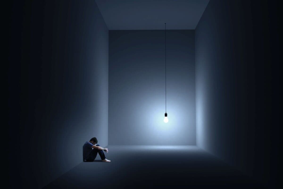 Ein Mann sitzt depressiv in einem Raum mit einer Glühbirne
