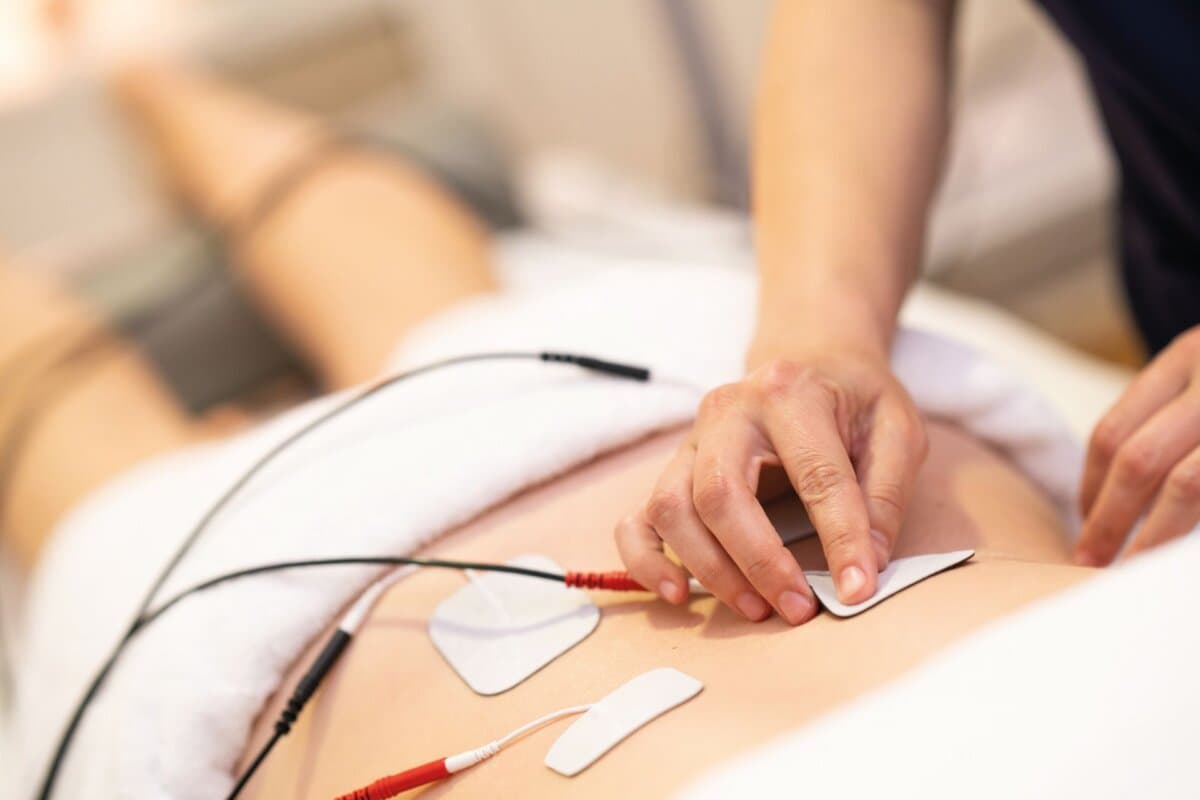 Physiotherapeutin appliziert TENS-Elektroden