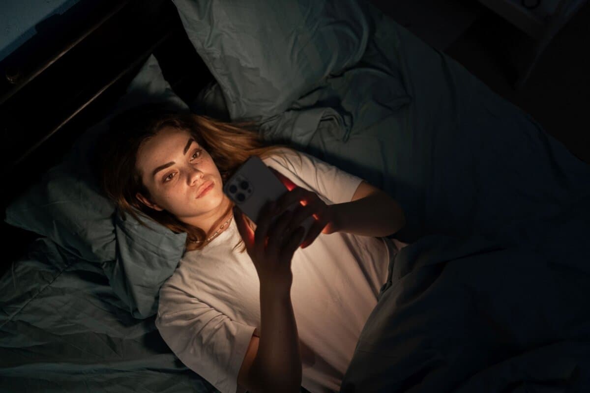 Angst, Schlaflosigkeit, Abhängigkeit. Eine Frau schaut nachts in ihr Smartphone.