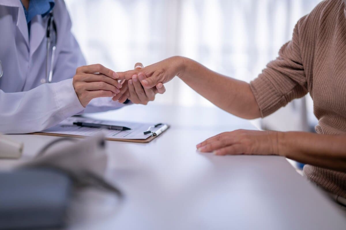 Ein Rheumatologe untersucht die Hände einer Patientin.