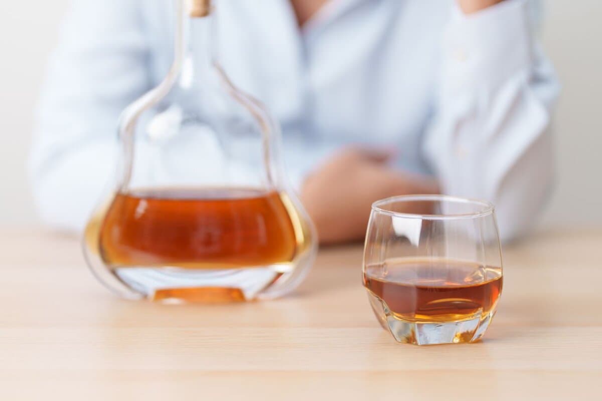 Ein Glas Cognac vor einem Mann – symbolisch für Alkoholabhängigkeit und problematischen Alkoholkonsum.
