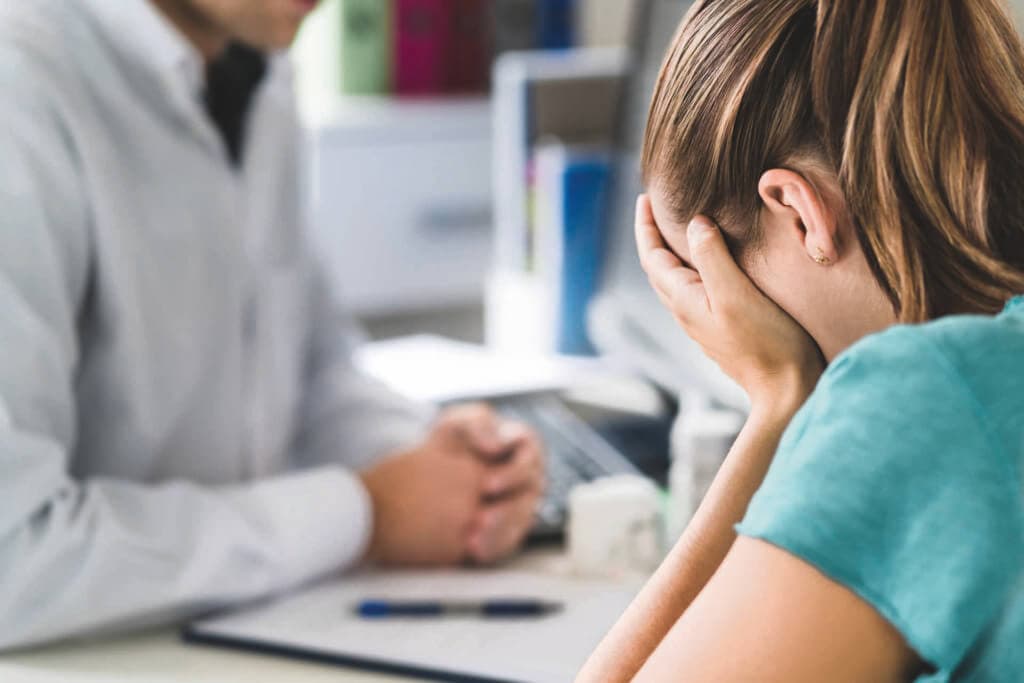 Sad patient visiting doctor. Young woman with stress or burnout