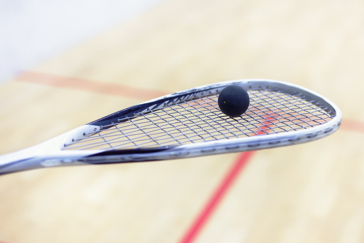 ein squash schlaeger mit einem squash ball in einer halle