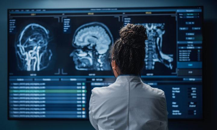 Schwarze Neurowissenschaftlerin, die auf den Fernsehbildschirm schaut, MRT-Bilder des Gehirnscans analysiert und eine Behandlung für den Patienten findet