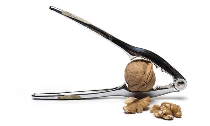 Close up of metal pliers to open nuts with walnut nutcracker on white background