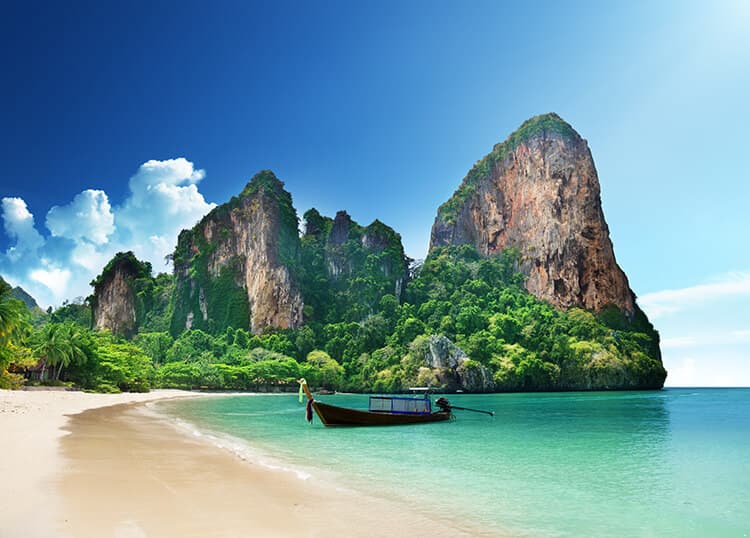 Malerische Landschaft auf Krabi in Thailand, Felsen im Meer, ein Fischerboot, das am Strand anlegt.