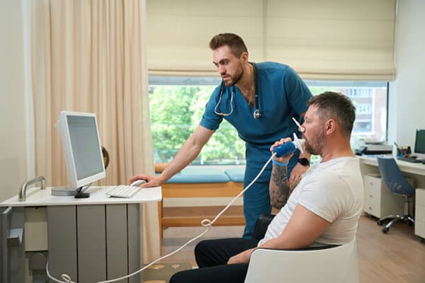 Homme adulte effectuant un test de spirométrie en présence d'un médecin