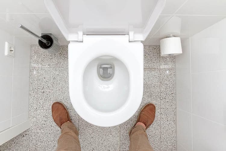 Mann steht vor einer Toilettenschüssel