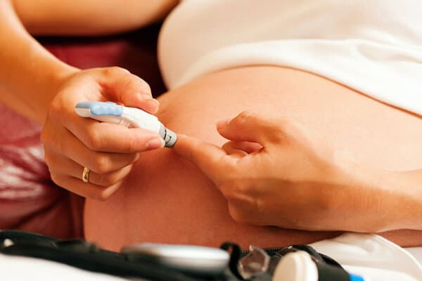 Schwangere Frau sticht sich in den Finger um den Blutzuckerspiegel zu messen.