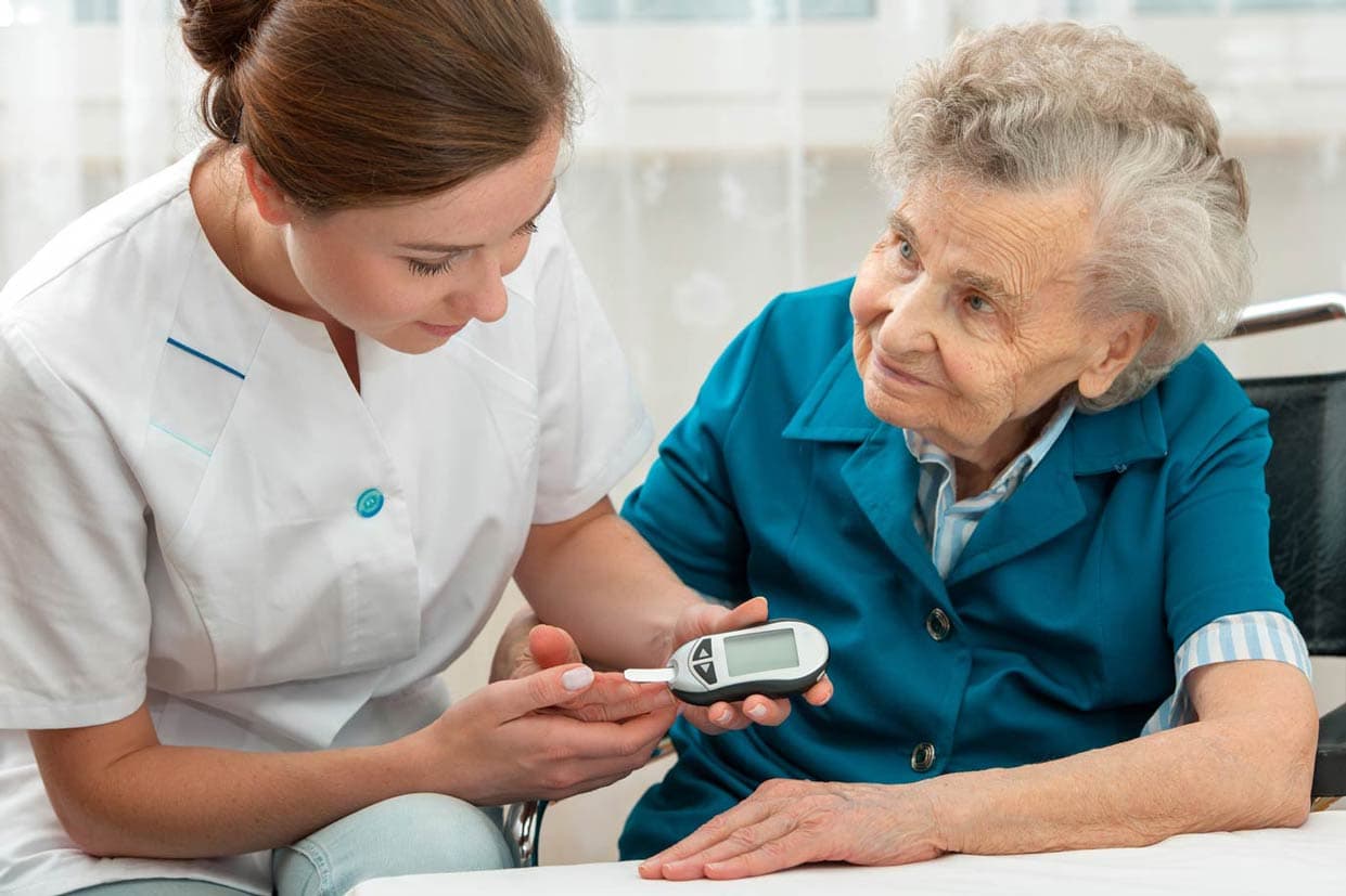 Krankenschwetser prüft Blutzucker von Seniorin